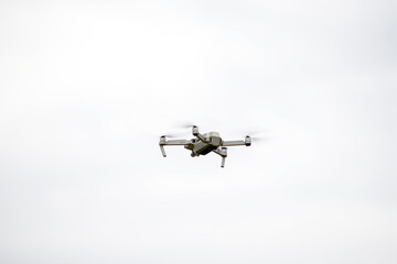 The quadcopter flies in height against the background of a gray sky.