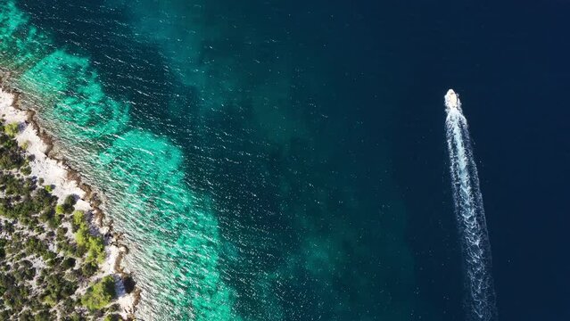 4K lonely motor boat moving near the turquoise Adriatic Sea coast waves. Aerial coastal top view 4K footage.