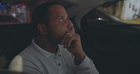 Upset young man covering face in anxiety while riding taxi cab in the backseat of car. One anxious...