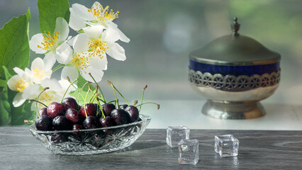 Fresh cherry in a vase. Still life with cherries. Crystal and unique, fresh smell of cherry. The light from the window illuminates the cherry still life. 
