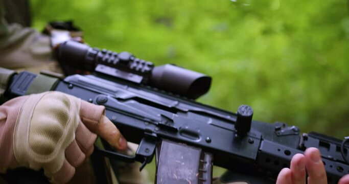 close-up of an automatic weapon in the hands of a soldier in the forest