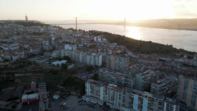 Aerial view of Cacilhas little town along the Tagus river at sunset with April 25th bridge and Cristo Rei statue in background, Almada, Portugal.