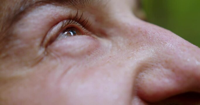 Male eyes that look up. A soldier in a helmet raises his head to the sky and laughs. The sweaty face of a bearded man. macro