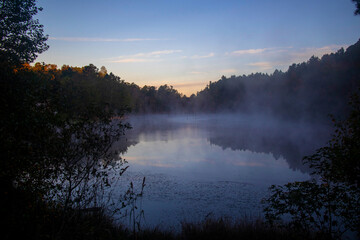 Fototapeta na wymiar Beautiful early morning foggy lake distant golden hour sky