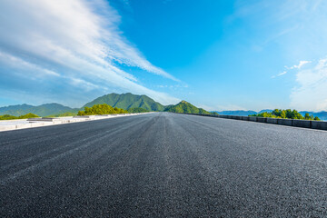 Straight asphalt road and green mountains with sky cloud background