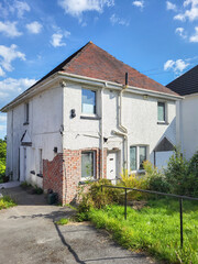 Large detached house awaiting refurbishment and improvement with driveway and cracked plaster work.