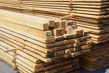 Wooden boards are stacked in a sawmill or carpentry shop. Sawing drying and marketing of wood. Industrial background - obrazy, fototapety, plakaty