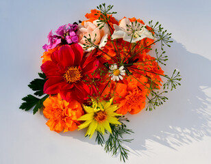 Top view of a floral arrangement of different flowers on a white background. Marigolds, dahlias, rose, petunia, chamomile, phlox and dill in one bouquet. Flower tolerance