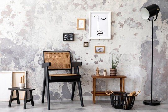 Loft style of modern apartment with design black chair, shelf, carpet and composition of wall art gallery. Minimalist home decor. Template. Grunge concrete wall.