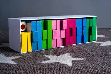 Stacking tower game of colorful wooden blocks. Jenga game of multi color  unevenly shifted wooden beams. A lesson for agility, logic and coordination. Home entertainment.