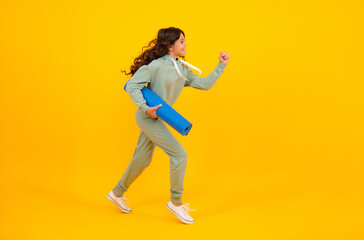 Fototapeta na wymiar Run and jump. Teenage girl dressed in sports uniform, posing in the studio. Child in a posh stylish sports suit in a hoodie with a hood. Advertising sportswear and yoga wear. Healthy kids lifestyle.