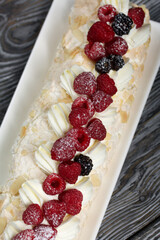Meringue roll with mascarpone cream. Garnished with raspberries and almond petals. Close-up.