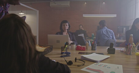 Group of people working inside corporate office at night. Young men and women employees in front of computers. Workspace and businesspeople concept. Millennials staff at work