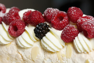 Meringue roll with mascarpone cream. Garnished with raspberries and almond petals. Close-up.