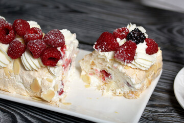 Meringue roll with mascarpone cream. Garnished with raspberries and almond petals. Close-up.