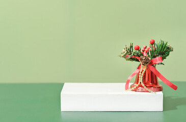 christmas decoration bell on white podium or pedestal on green background. copy space for product placement, holiday sale.