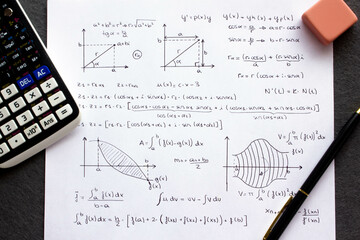 Sheet of paper with science background and math formulas written by hand with calculator, pen and...