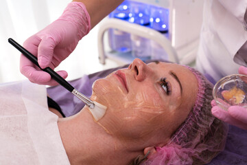 A beautician applies cooling gel and prepares skin for cosmetology procedure. 