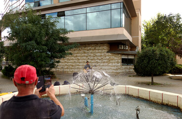 man recording a street performance of a guitarist with his mobile phone, 