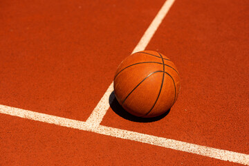 Top view orange ball for basketball lying on the rubber sport court. Sport red ground outdoor in...