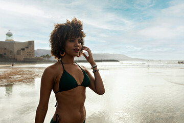 Portrait of a beautiful black woman in swimsuit with beach background.