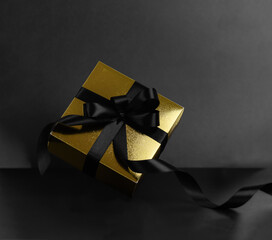 Gold Gift box and black ribbon on black background