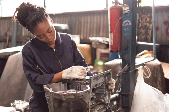 African american technician female Mechanic working under the hood at the repair garage.