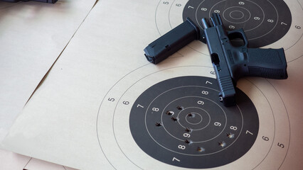 A black handgun and a paper target with bullet marks.