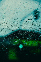 parabrisas con gotas de lluvia con luz de semáforo desenfocado en día nublado
