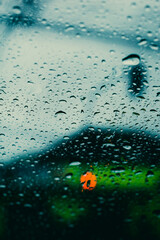 parabrisas con gotas de lluvia con luz de semáforo desenfocado en día nublado