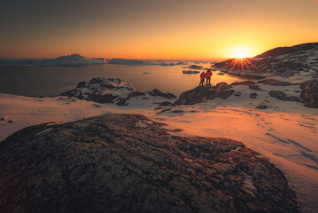 Photographers taking picture of sunset in greenland during winter next to ilulissat icefiord