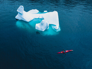 Kayak on the sea in Greenland next to big icebergs close to Ilulissat icefiord, aerial view