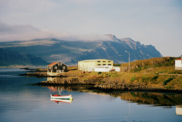 Obraz premium Houses and a boat on the lake with mountain views in Iceland. Grainy film in the style of old photos. High quality photo