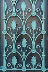 Closeup view of beautiful design of water green color wrought iron panel with holly leaves motif on glass background