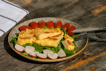 A light breakfast of French omelet with radishes, spinach tomatoes and arugula. European Breakfast