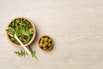 Fresh salad with arugula, spinach and vegetables on wooden background, top view