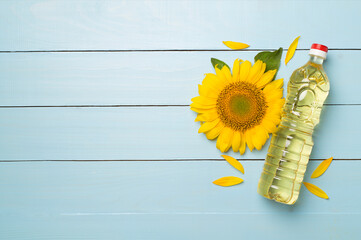 Sunflower oil and flower on wooden background, top view