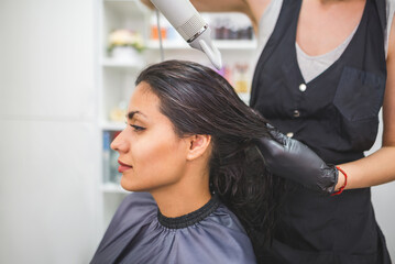 Fototapeta premium Drying long dark hair with a hairdryer.