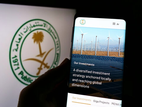 Stuttgart, Germany - 12-18-2021: Person holding smartphone with webpage of Saudi Arabian Public Investment Fund (PIF) on screen in front of logo. Focus on center of phone display.