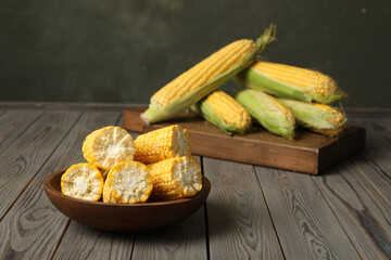 Tasty sweet corn cobs on wooden table. Space for text