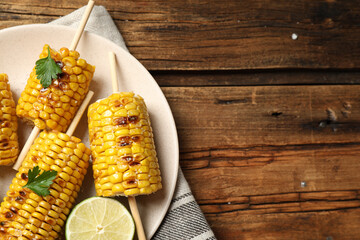 Tasty grilled corn on wooden table, top view. Space for text