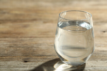 Glass of water on wooden table, closeup with space for text. Refreshing drink