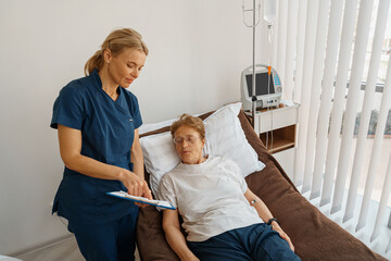 Nurse in uniform explain to patient results of analysis standing in hospital ward in clinic - obrazy, fototapety, plakaty