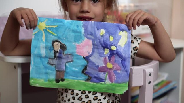 Talented Creative Child Girl Female Artist Draws Ranbow Mother summer on Paper, Child showing her work.Creates Colorful, Kid Drawing on table at Home. Painter Creating Abstract Modern Art. Childhood