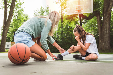Mother and little daughter play basketball outside crying because of ankle accident