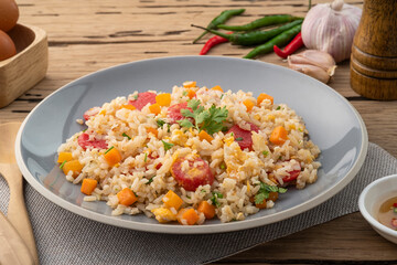 Sausage Fried rice.Stir fried Thai rice with hot dog ,carrot and eggs in gray plate on wood table