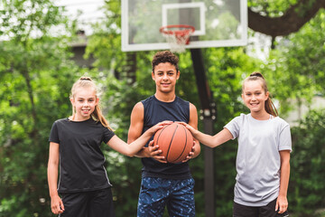 three teens in sportswear playing basketball game