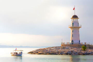 The old lighthouse and fishermen boat in the port of the Turkish city of Alanya at sunrise....