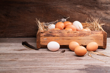 Chicken eggs are laid on the ground and put in a basket on a wooden table on, a rural farm