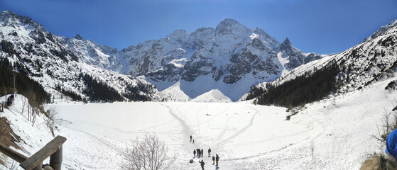 morskie Oko lake covered in ice at winter in Tatra Mountains. tourists on a snowy lake. Zakopane, Poland © Svitlana
